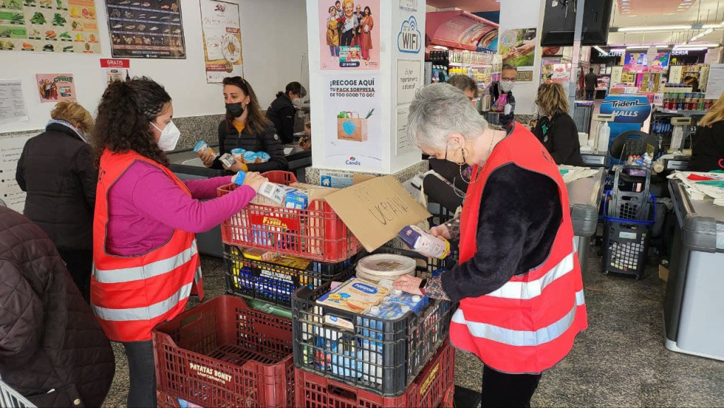 Persones voluntaries recollint material i aliments al supermercat