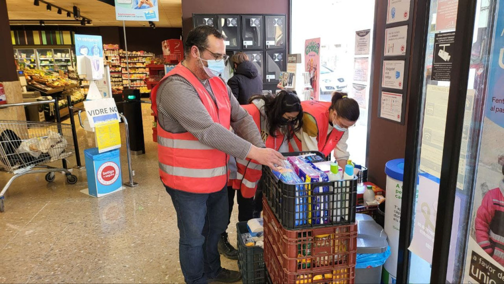 Persones voluntaries recollint material i aliments al supermercat