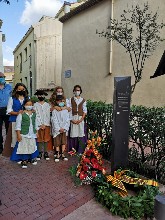 Nens i nenes fent l'ofrena floral al totem del Memorial 158